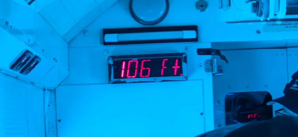 Guest photo of a red digital depth gauge in the submarine cabin reading 106 feet