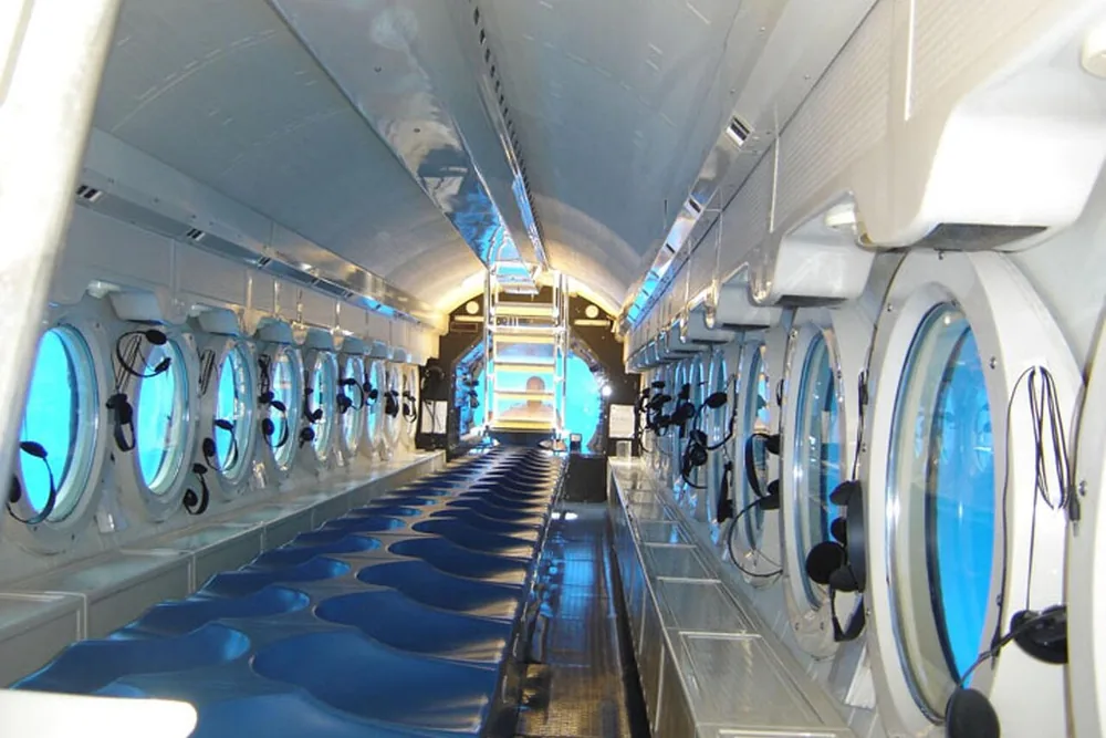 The inside of a long submarine cabin with rows of round portholes on both sides
